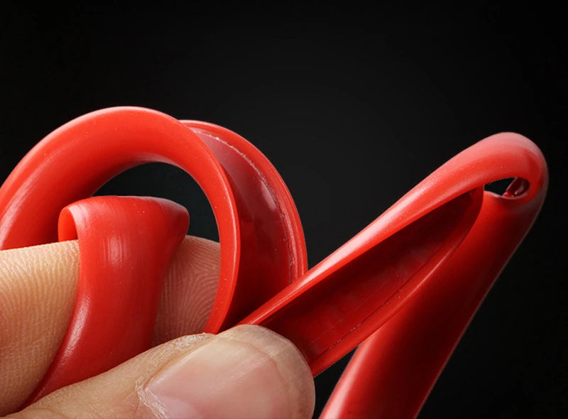 A hand is holding a red car wheel rim protector trim, showing its curved shape and texture against a dark background.