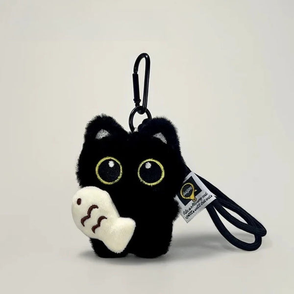 Clé portkey de chat en peluche noire avec des yeux jaunes et une patte blanche, attachée à un cordon noir.