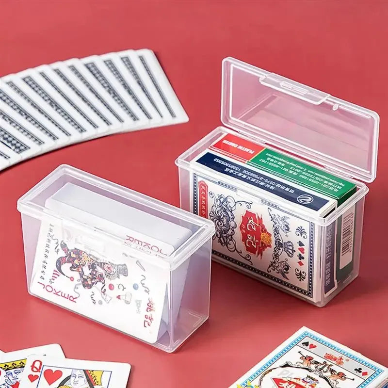 A clear plastic storage box with a lid and an open tray is shown next to a stack of playing cards.