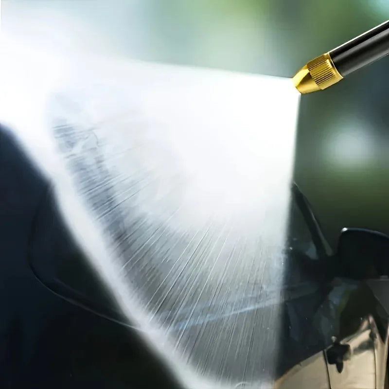 A high-pressure car wash gun is spraying a powerful stream of water onto a dark surface.