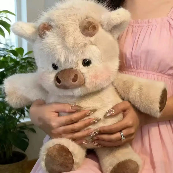 A person is holding a fluffy white Highland cattle plush toy against a pink dress.
