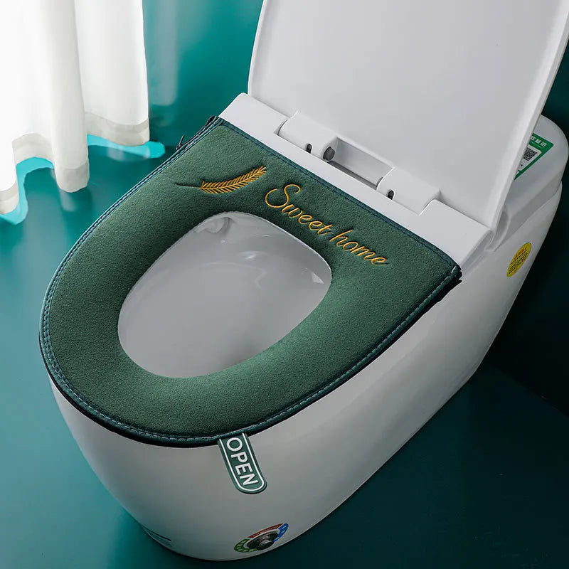 Tapa de asiento de inodoro blanca con cojín verde y texto 'Sweet home', abierta en el inodoro.