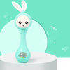 A light blue musical rabbit rattle and teether toy is displayed on a white surface against a teal background.
