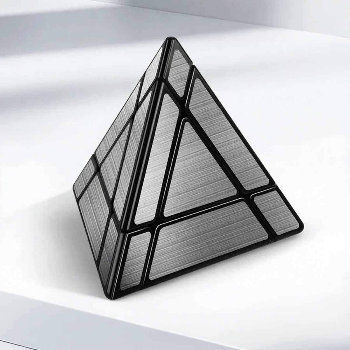 A black geometric cube puzzle with a faceted surface resting on a white surface.
