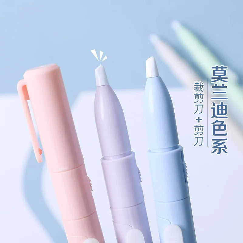 Three colored folding pen-shaped safety scissors displayed vertically against a light blue background.