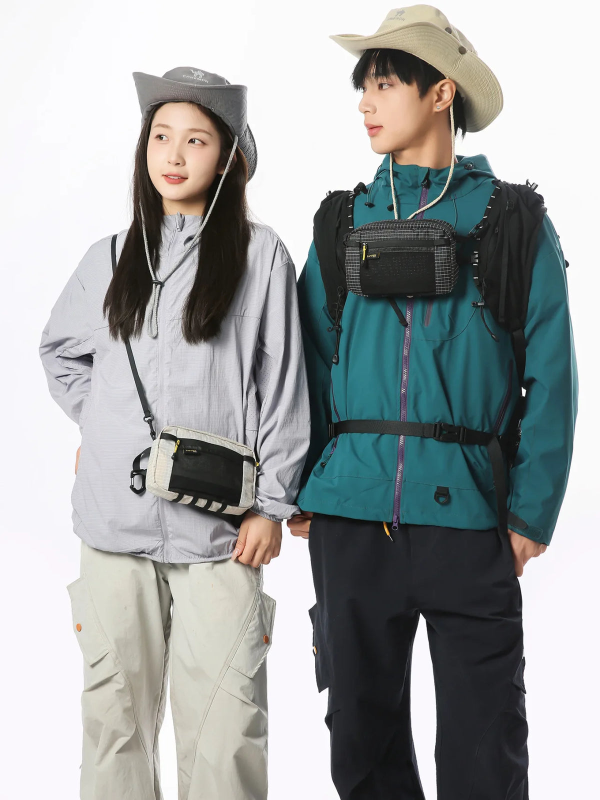 A young man and woman wearing outdoor tactical gear, including a waterproof vest and waist bag.