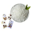 White natural soy wax granules in a bowl with small dried floral elements.