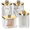 Elegant apothecary jars with golden lids for storing cotton balls and swabs.