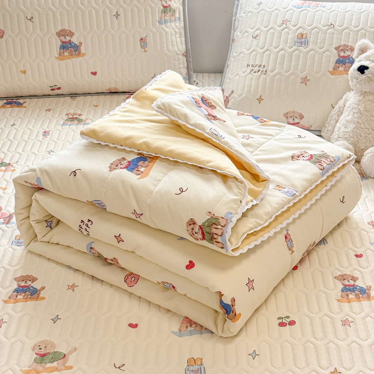 A stack of cream-colored lace-trimmed breathable summer duvets with embroidered animals on a quilted surface.