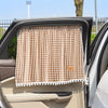 A brown and white checkered sun shade curtain is shown installed in the window of a car.