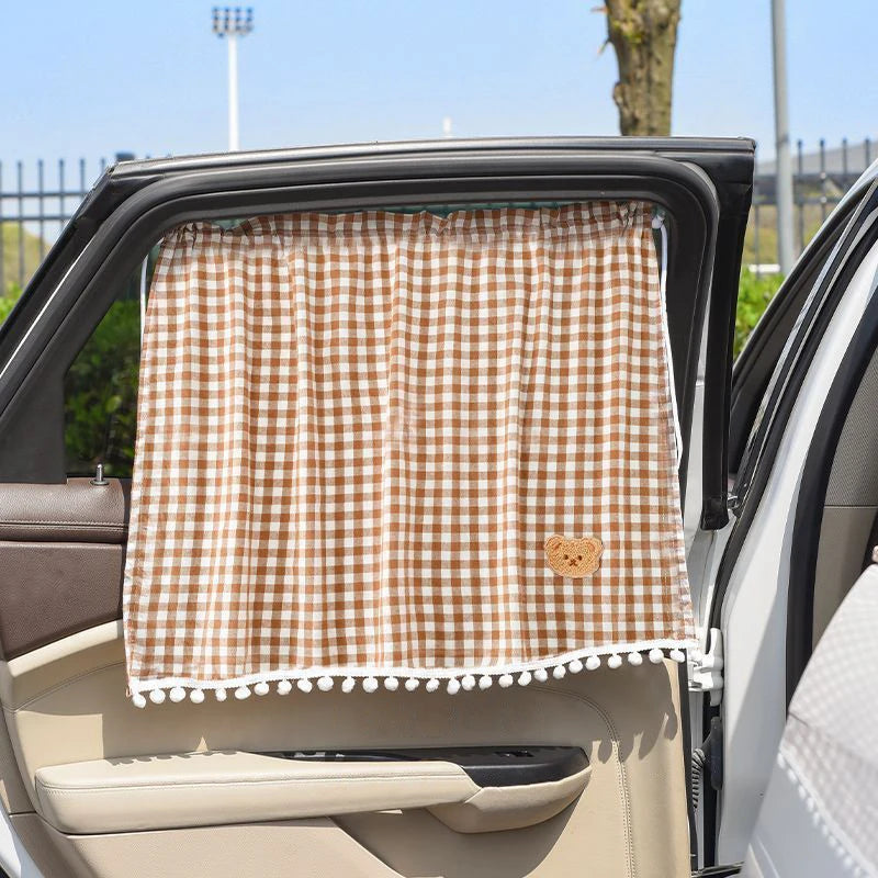 A brown and white checkered sun shade curtain is shown installed in the window of a car.