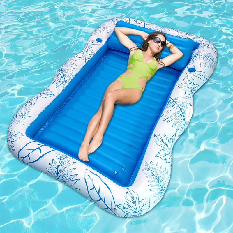 Une femme se relaxant sur un transat de piscine gonflable bleu avec des motifs de feuilles flottant dans l'eau claire.