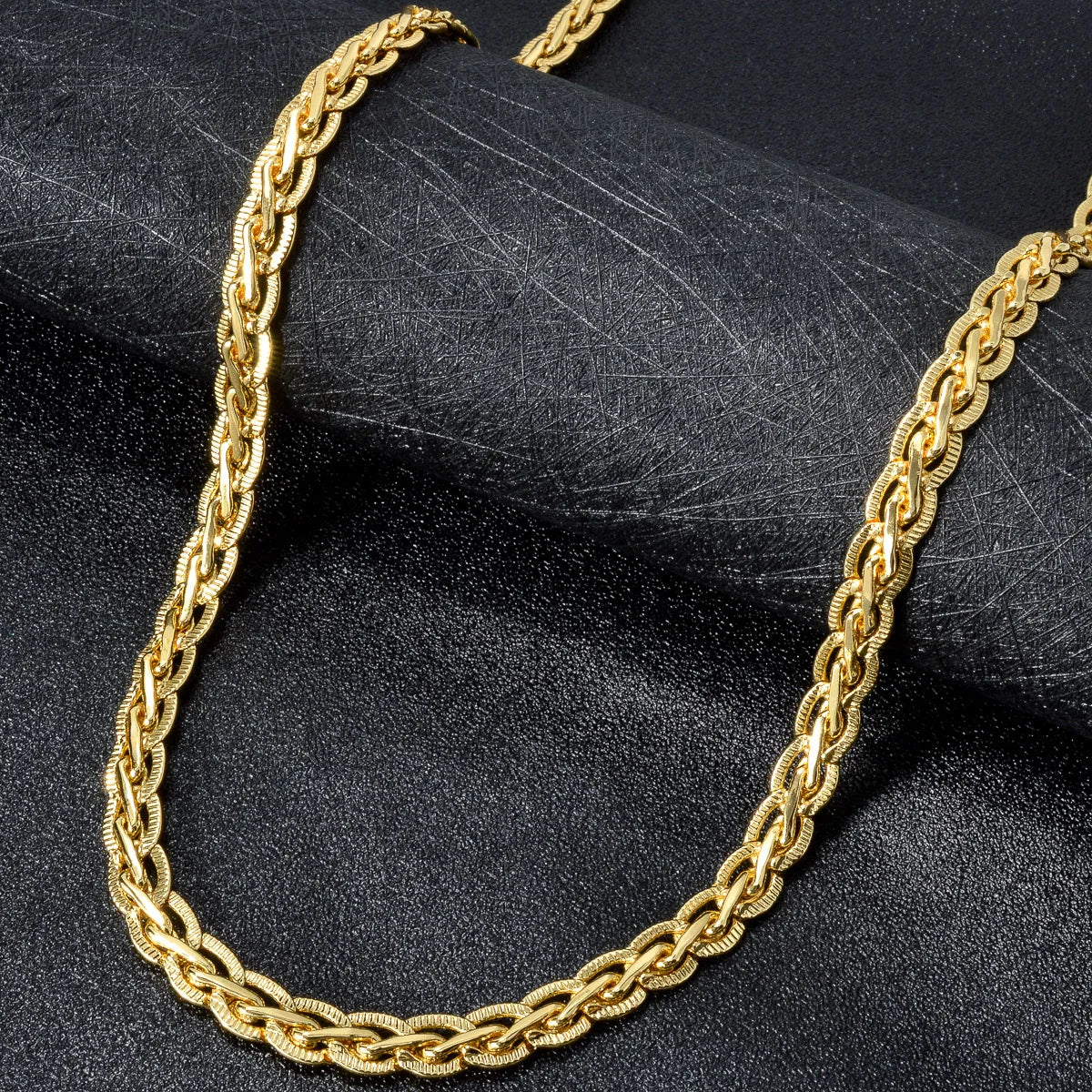 Nahaufnahme einer goldvergoldeten Cuban-Kettenkette auf dunklem Stoff.
