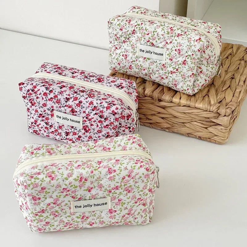 Three floral quilted makeup bags in pink and green patterns are displayed on a woven basket.