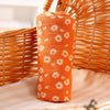 Orange muslin baby swaddle blanket rolled up, resting on a woven basket.