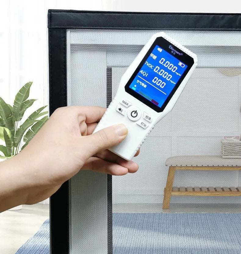 A hand holds a digital mosquito net screen device with a display showing 0.000 and controls, placed in front of a window fram