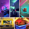 A modern interior featuring vibrant RGB LED strip lights illuminating a bar area and a television screen.