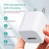 A hand holds a white compact USB wall charger with built-in safety features.