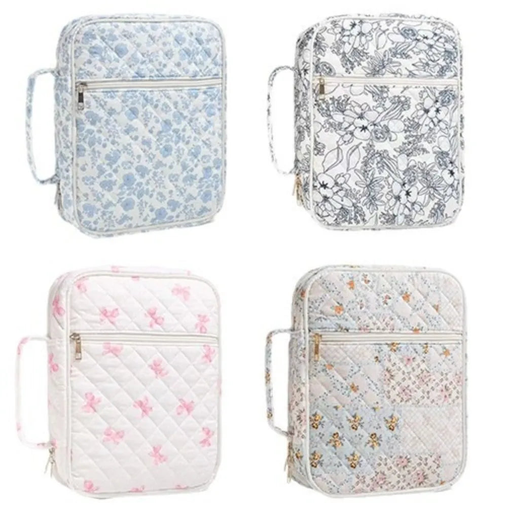 A collection of floral quilted Bible covers in light blue, gray, and white patterns with zipper pockets and carry handles.