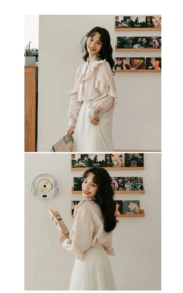 A woman models a white vintage lace long sleeve blouse against a light wall with framed photos.