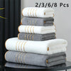 A stack of luxury bath towels in white and gray with gold accents.