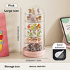 A pink rotating transparent display box filled with small collectible figures and animals.