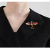A close-up of a black blazer featuring an enamel dragon brooch with gold and rhinestone accents.