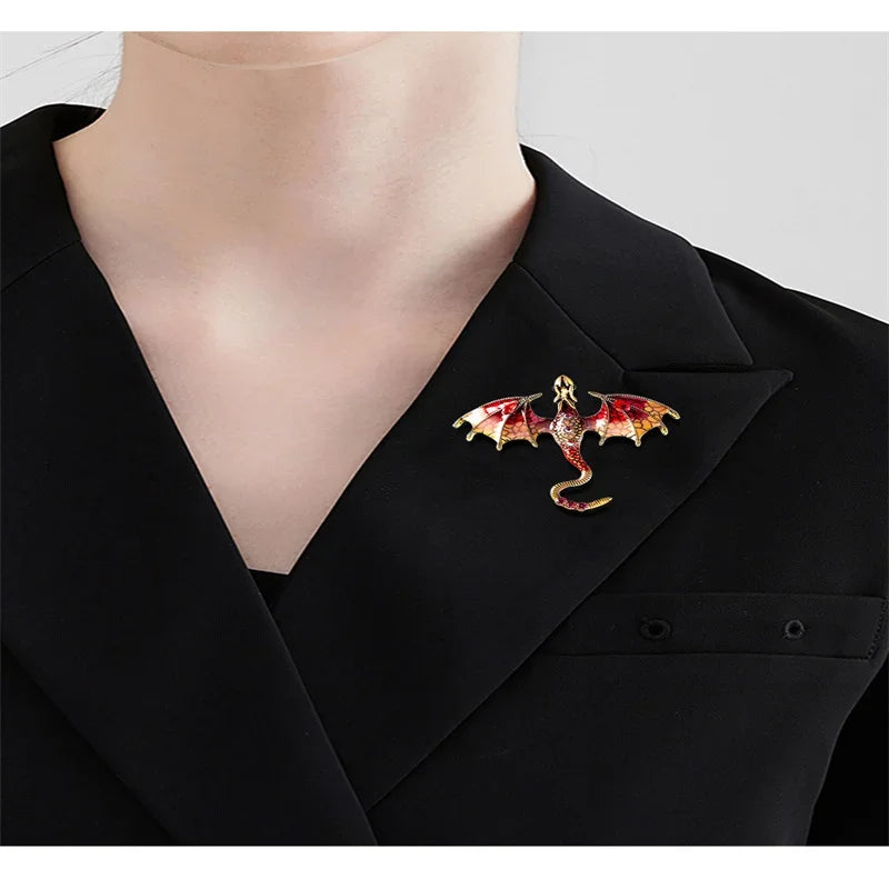 A close-up of a black blazer featuring an enamel dragon brooch with gold and rhinestone accents.