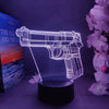 A glowing outline of an old gun shape night light displayed on a dark surface next to a book and pink flowers.
