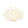 A pile of small, round, off-white imitation pearl beads for jewelry making.