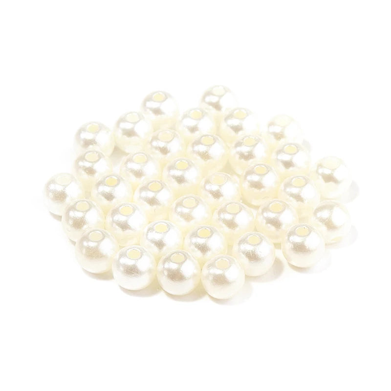 A pile of small, round, off-white imitation pearl beads for jewelry making.