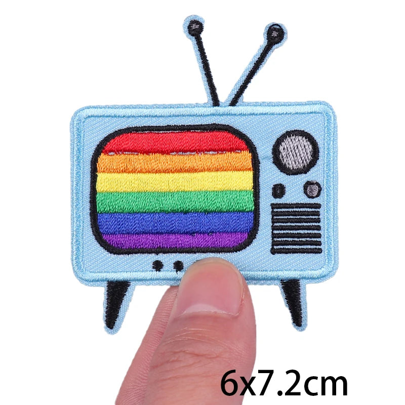 A light blue embroidery patch depicting a retro television with rainbow stripes and antennae.