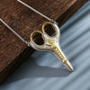 Vintage stainless steel sewing scissors with gold accents hanging from a silver chain