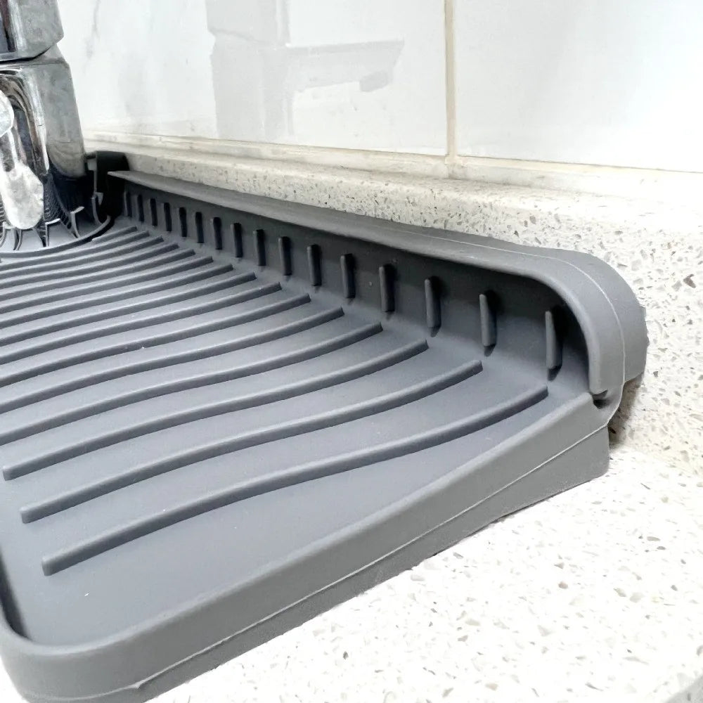 A gray silicone faucet splash mat designed to catch water on a countertop.