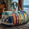 A quilted travel duffle bag featuring blue and orange fabric with colorful stitching and handles resting on a wooden surface.