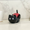 A black cat-shaped soap box with a red drainage tray sits on a white countertop.