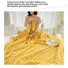 A yellow, textured fleece throw blanket is draped on a bed, emphasizing its soft, cozy texture.