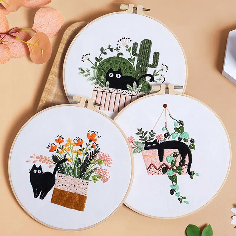 Embroidery kit featuring pre-printed floral and cat designs on white fabric with wooden hoops.
