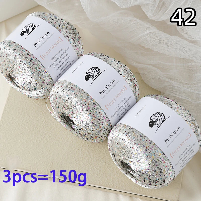 Three balls of glitter yarn labeled MuYuan Frost Words are displayed on a light surface.