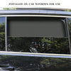 A magnetic car window sunshade installed on a vehicle window, blocking the view of trees and foliage.