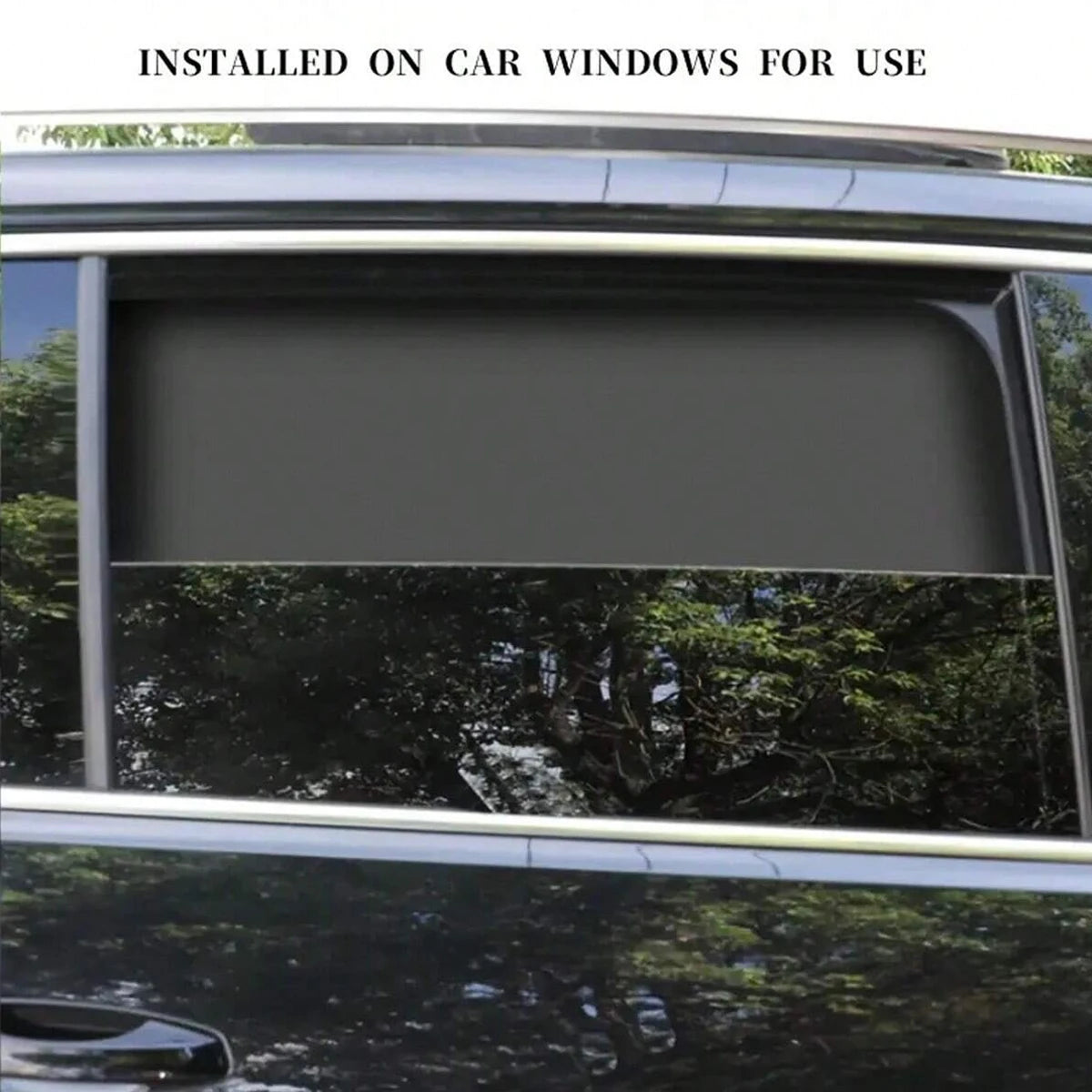 A magnetic car window sunshade installed on a vehicle window, blocking the view of trees and foliage.