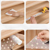 A hand is using a plastic mat with daisy flowers to wipe a wooden kitchen drawer.