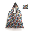 A reusable shopping tote bag featuring a pattern of various leaf shapes in shades of blue, green, and orange.