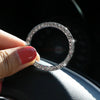 A hand holds a circular crystal rhinestone start/stop button cover against a dark background.