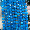 A hand holds a strand of bright blue natural stone square faceted beads for jewelry making.