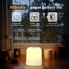 A white touch-activated LED night light is displayed on a wooden table next to various household items.