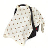 A beige stroller cover with a white background and small brown hearts pattern, featuring black straps.