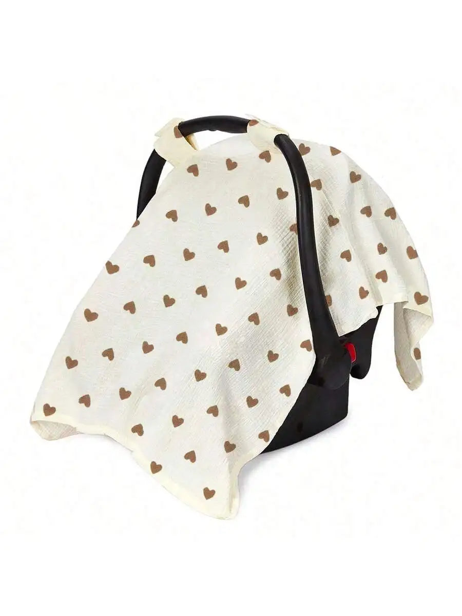 A beige stroller cover with a white background and small brown hearts pattern, featuring black straps.