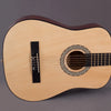 A light-colored classical guitar with a dark wood finish and a decorative rosette on the soundhole.
