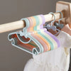 Colorful plastic hangers with bow designs hanging from a wooden rod.
